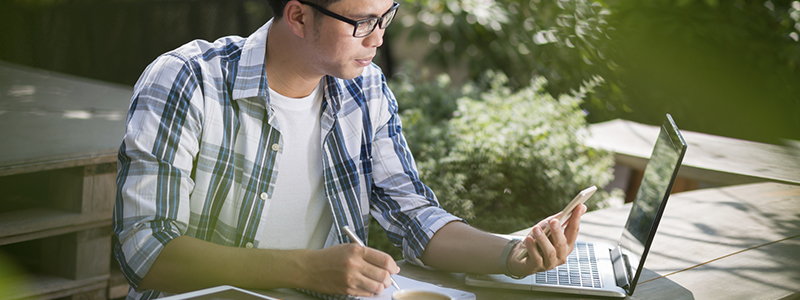Estudiante concentrado preparando oposición en su escritorio con portátil y cuaderno
